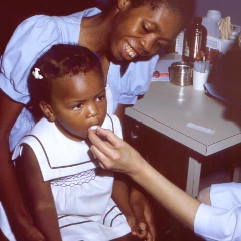 A young child receiving an oral polio vaccine.