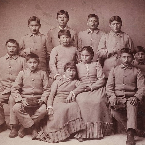 A group of Apache Native American children pose for a portrait four months after arriving at Carlisle Industrial Indian School.