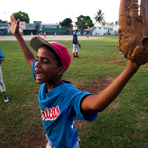 A young Dominican boy argues a call with the umpire during a practice game.