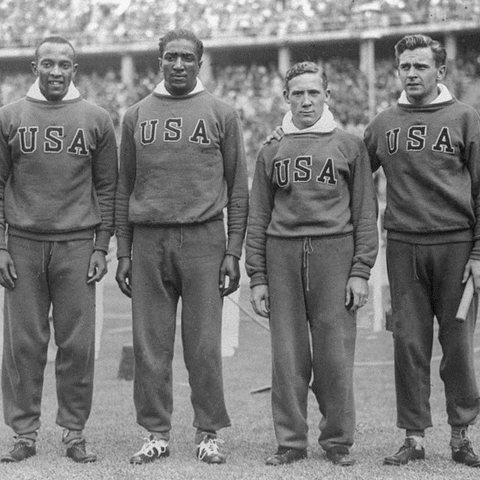 Jesse Owens and Ralph Metcalfe stand with their 4x100 metres relay teammates.