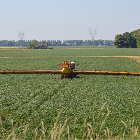 An industrial farm spraying pesticide on crops.