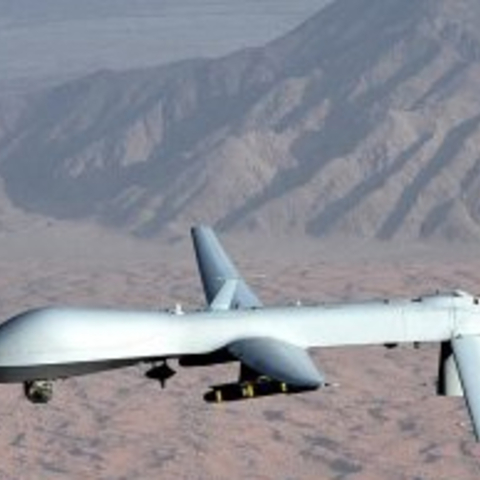 a military drone in the air over a desert