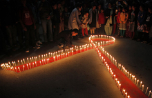 A red AIDS ribbon outlined in candles