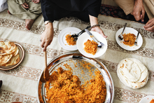 Top view of person serving themself a rice dish from a table of food