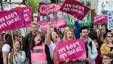 A group of men and women. The women hold signs that say "My Body, My Choice"