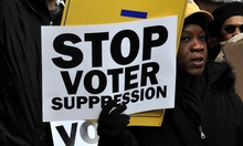 Person holding sign that reads "Stop Voter Suppression"